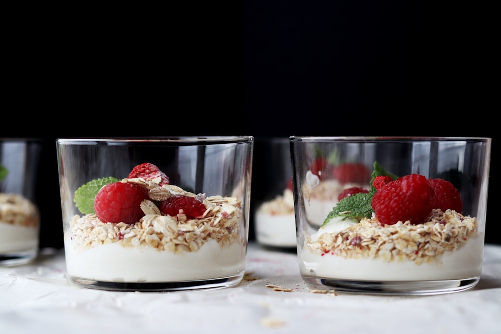 three glasses of yogurt with raspberries and granola