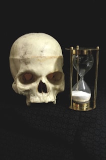a human skull next to an hourglass