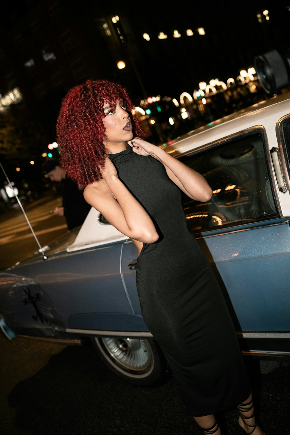 a woman with red hair standing next to a car