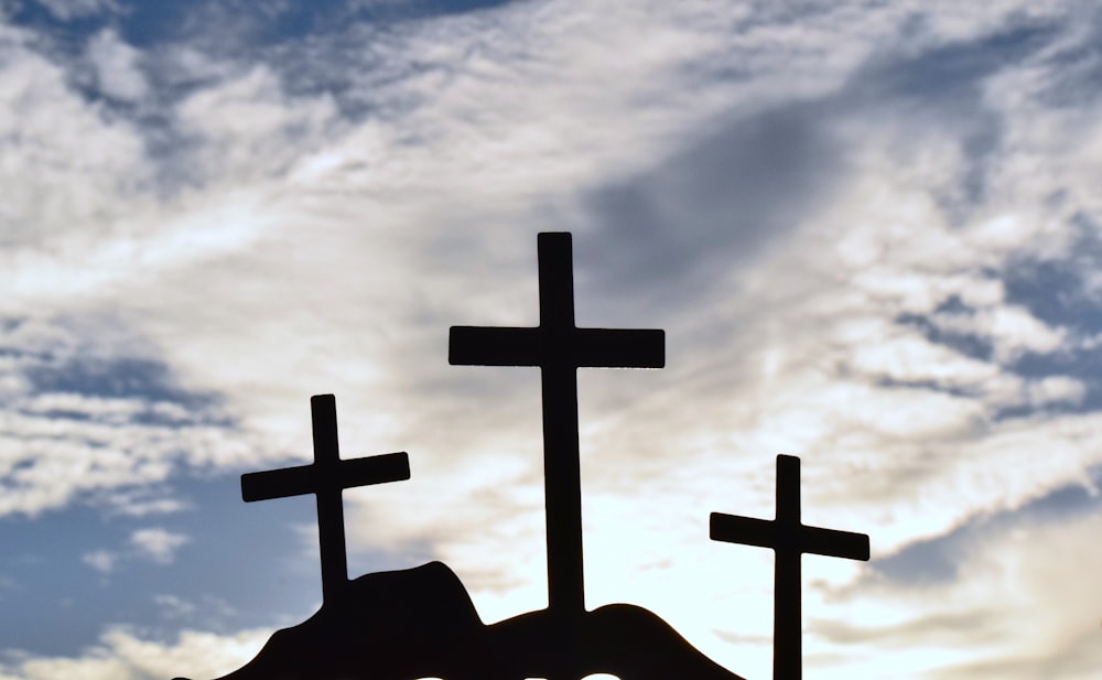 the silhouette of three crosses against a cloudy sky