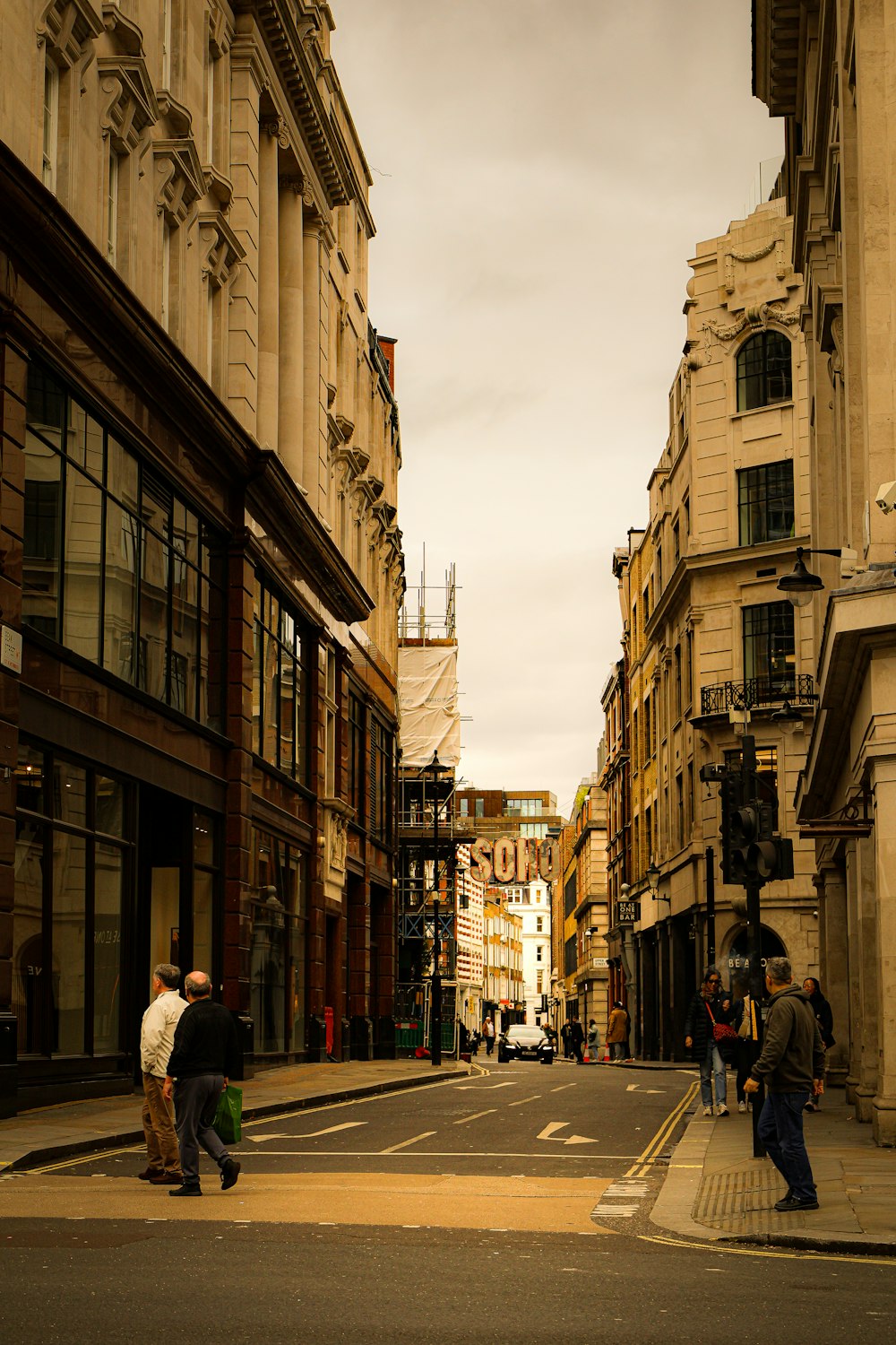 a group of people walking down a street next to tall buildings