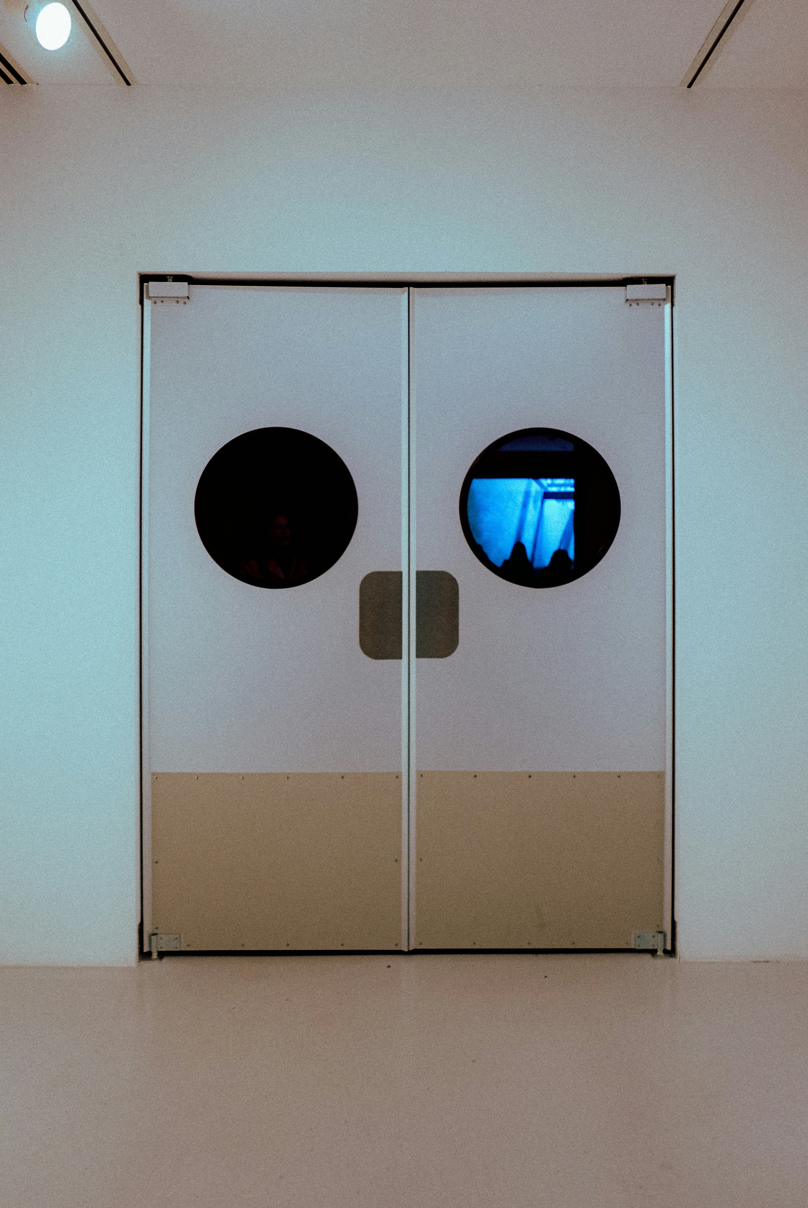 a white room with two round windows and a white wall