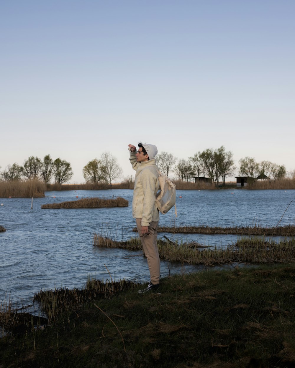 a woman in a white coat is standing by a body of water