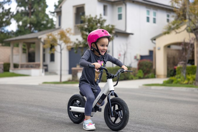 A young girl riding a small bike on a quiet street, the kind of practice the Boulevard Mall traffic garden is built for
