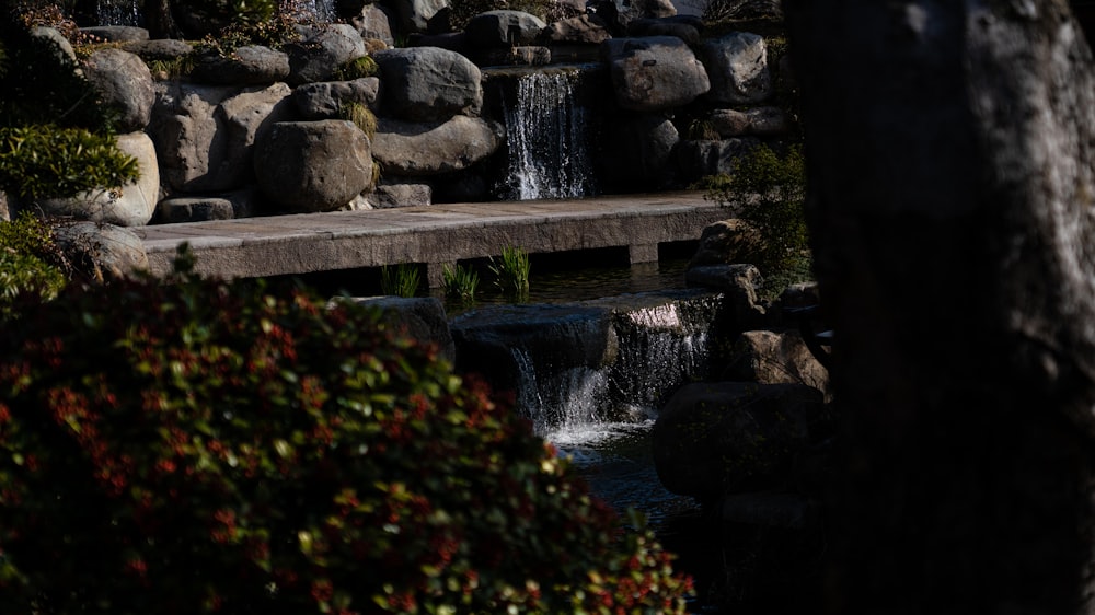 a bench sitting next to a small waterfall