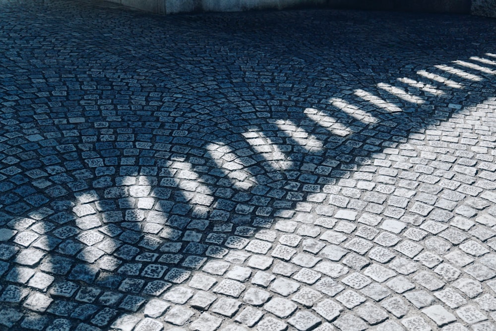 Der Schatten eines Fahrrads auf einer Kopfsteinpflasterstraße