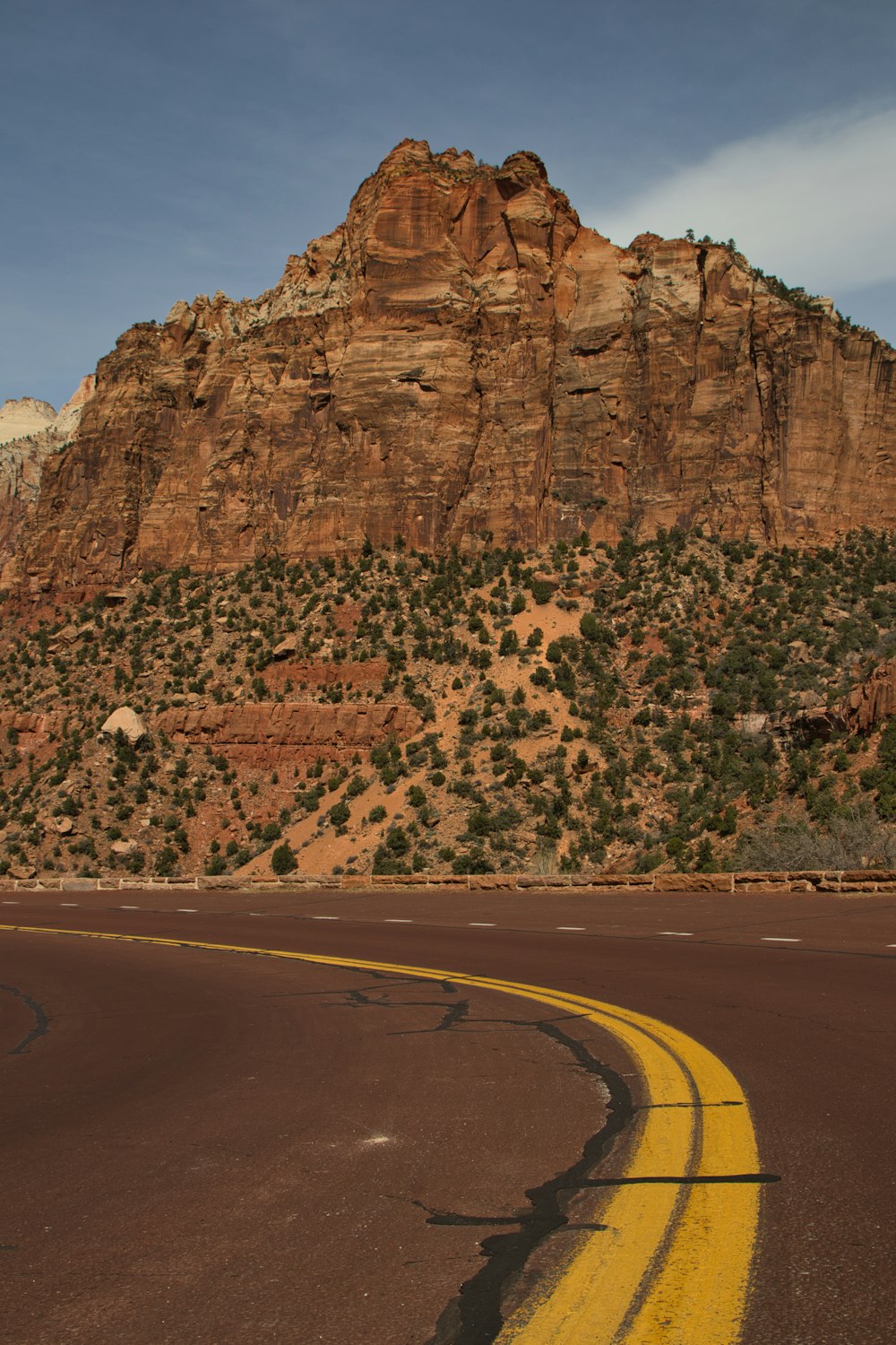 a yellow line on a road in front of a mountain