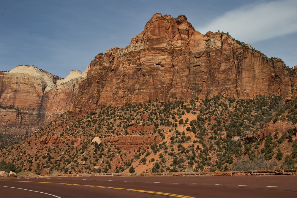 a car driving down a road in front of a mountain