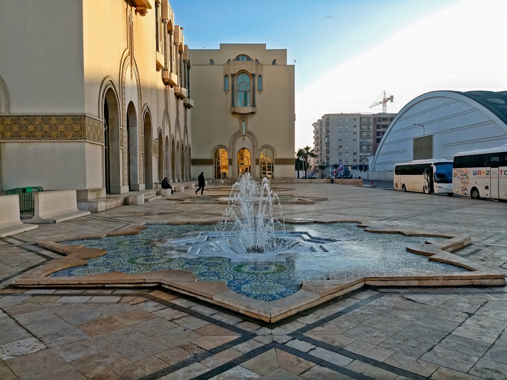 a fountain in the middle of a courtyard with a building in the background