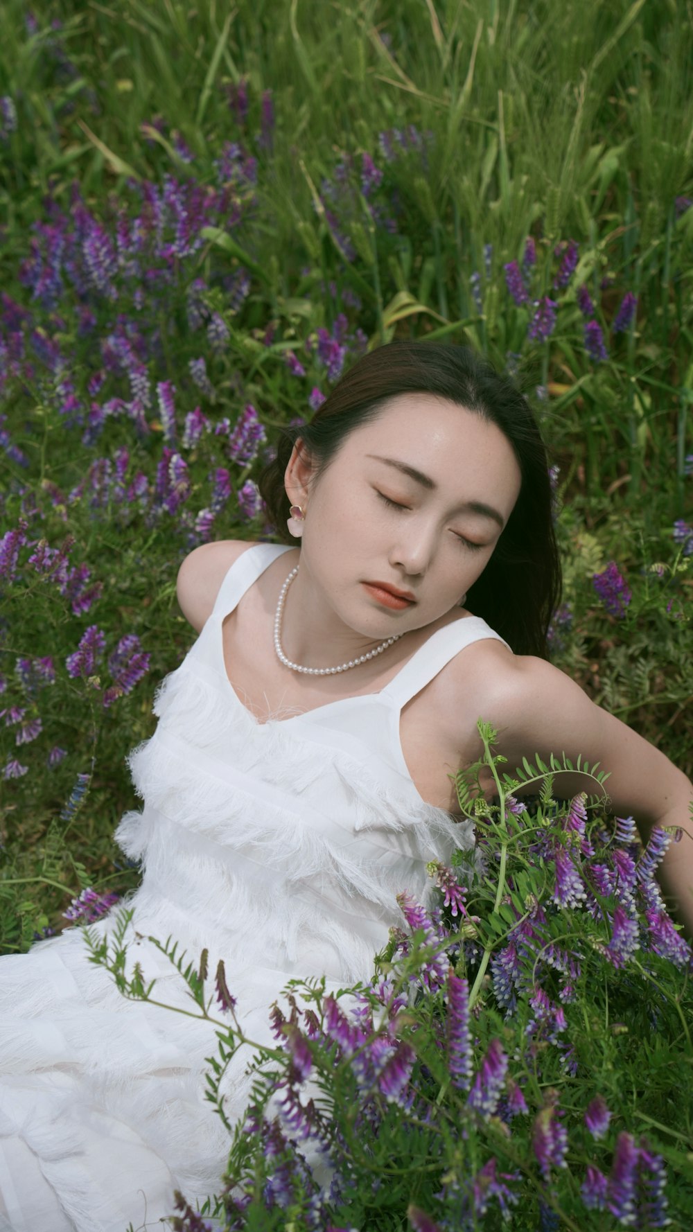 a woman in a white dress laying in a field of purple flowers