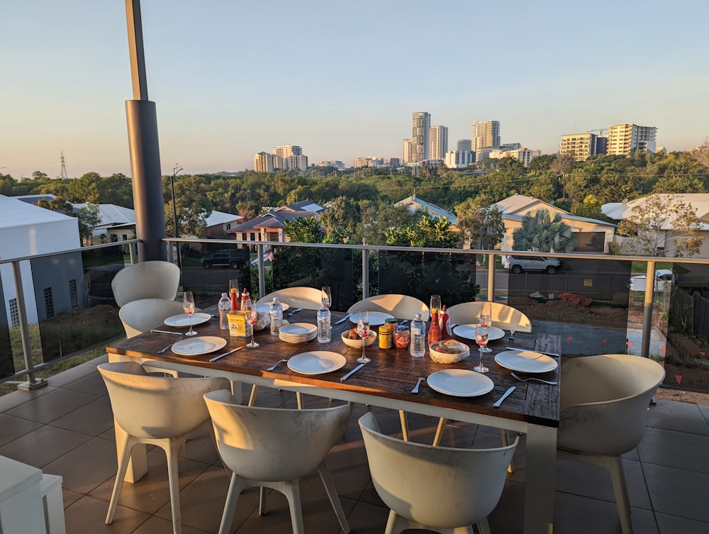 a table set with plates and silverware on a balcony overlooking a city