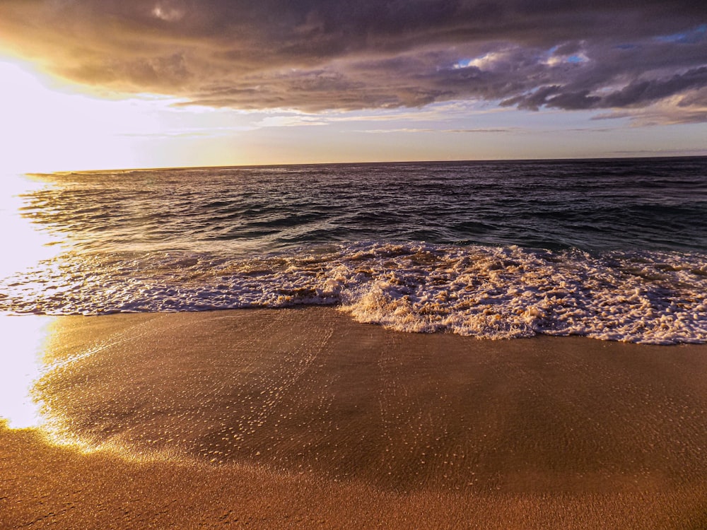 a sandy beach with waves coming in to shore