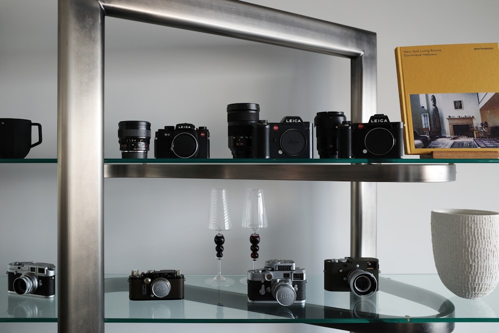 a glass shelf with a bunch of cameras on it