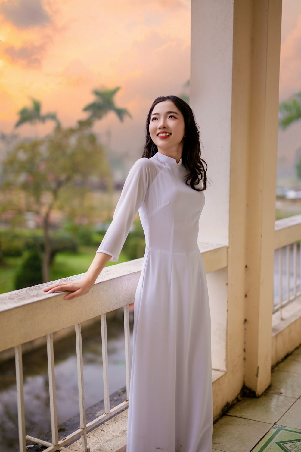 a woman in a white dress standing on a balcony