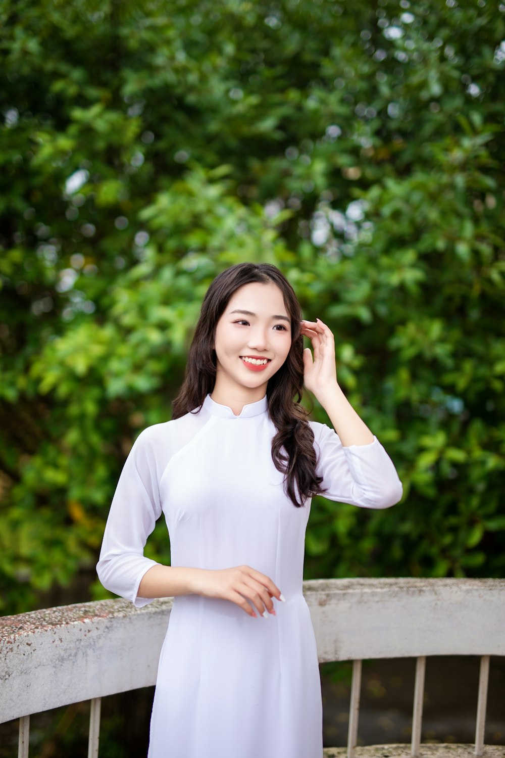 a woman in a white dress standing on a bridge