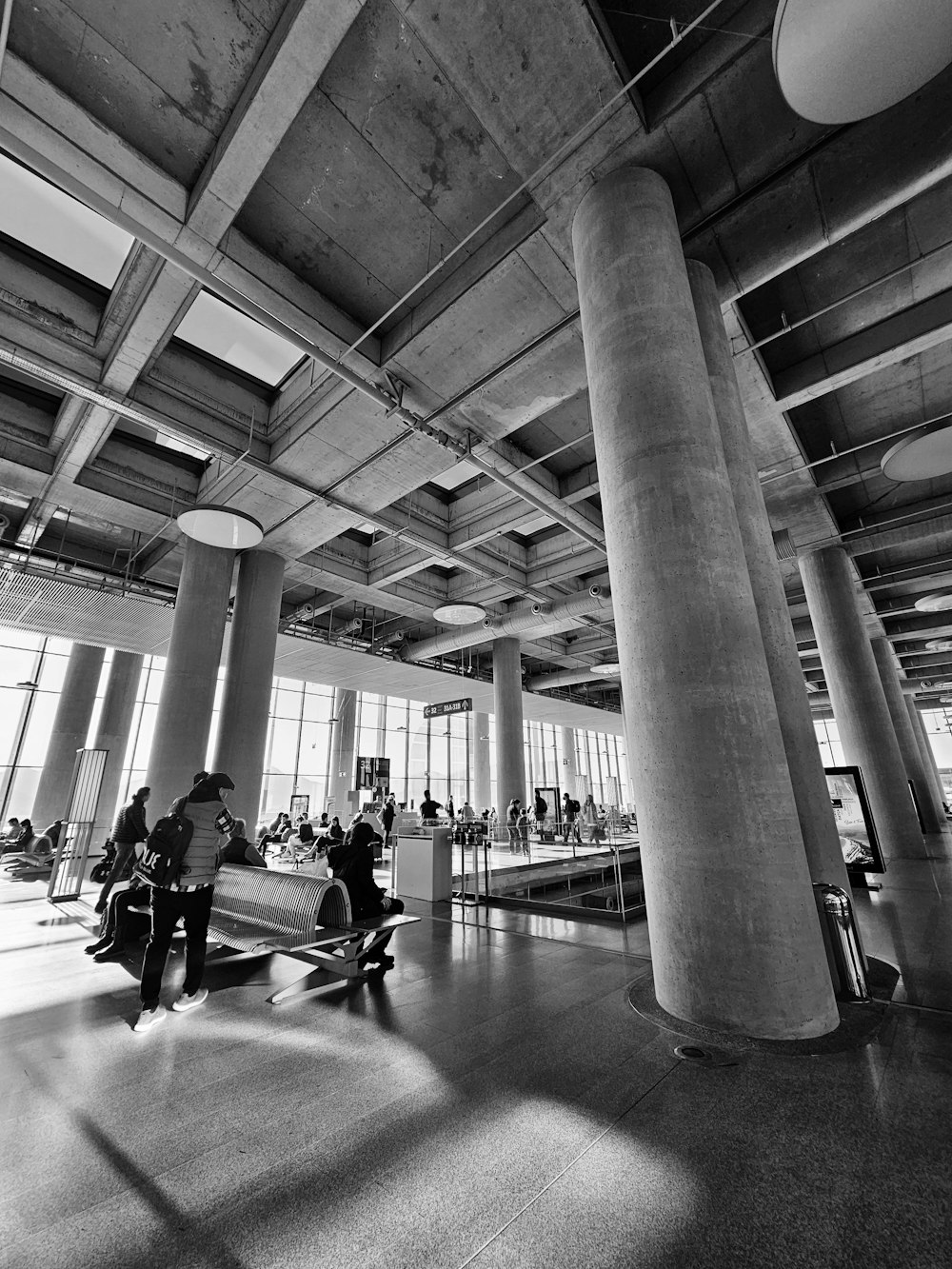 a black and white photo of people sitting in a lobby