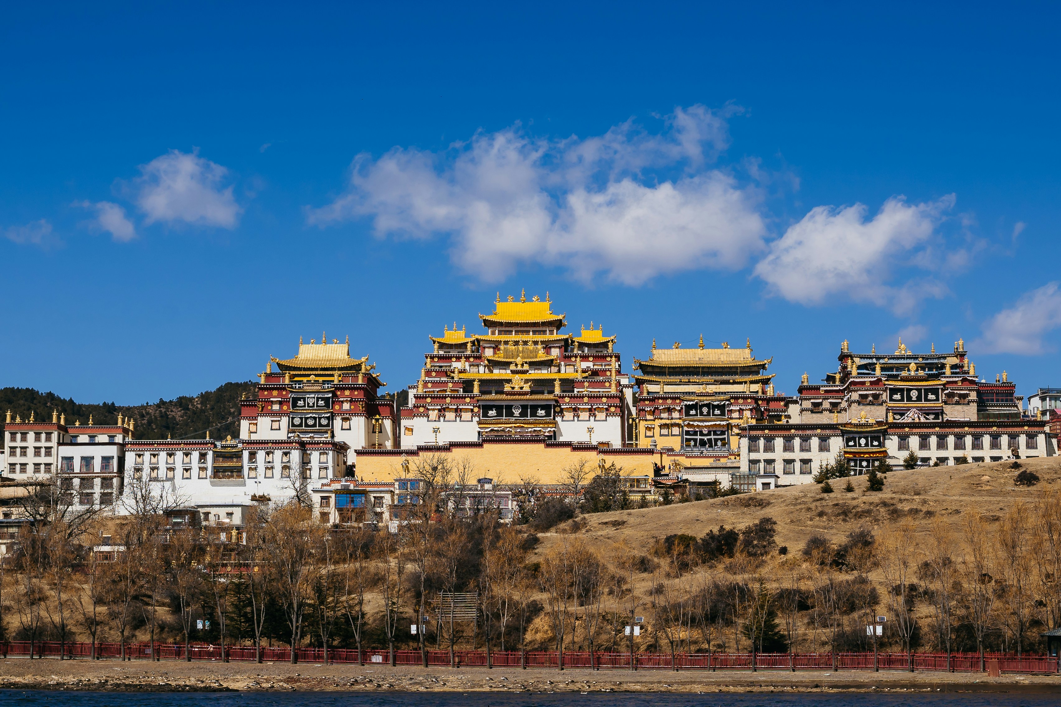 a group of buildings sitting on top of a hill next to a body of water