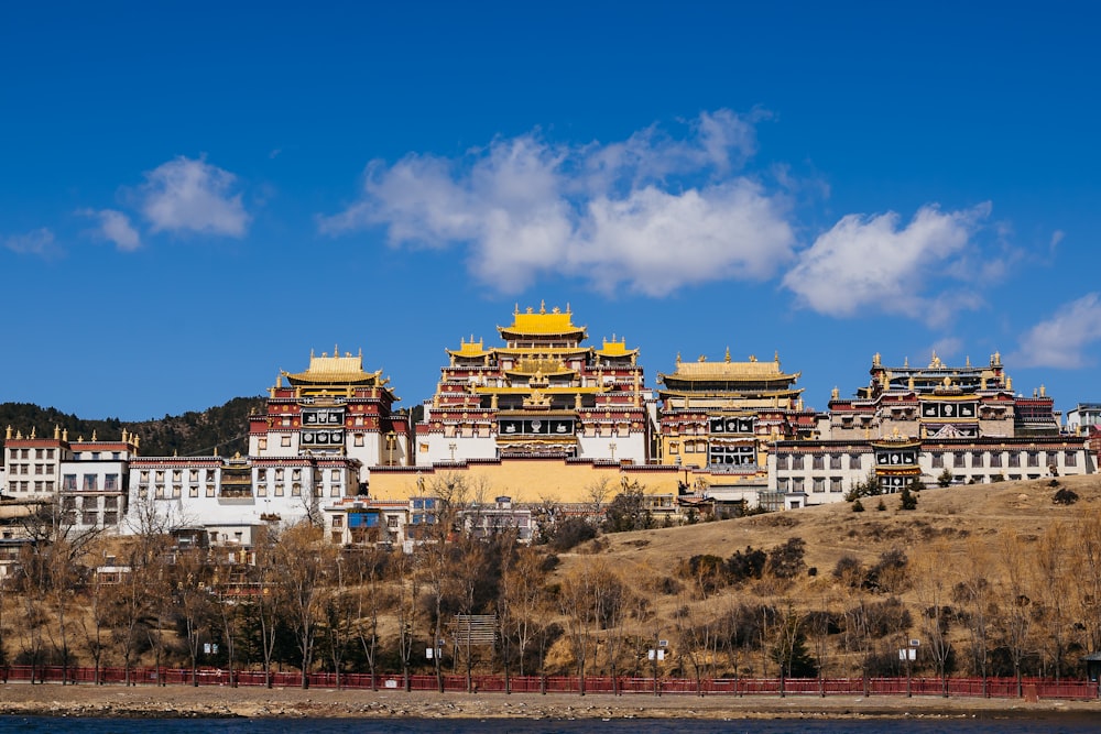 a group of buildings sitting on top of a hill next to a body of water