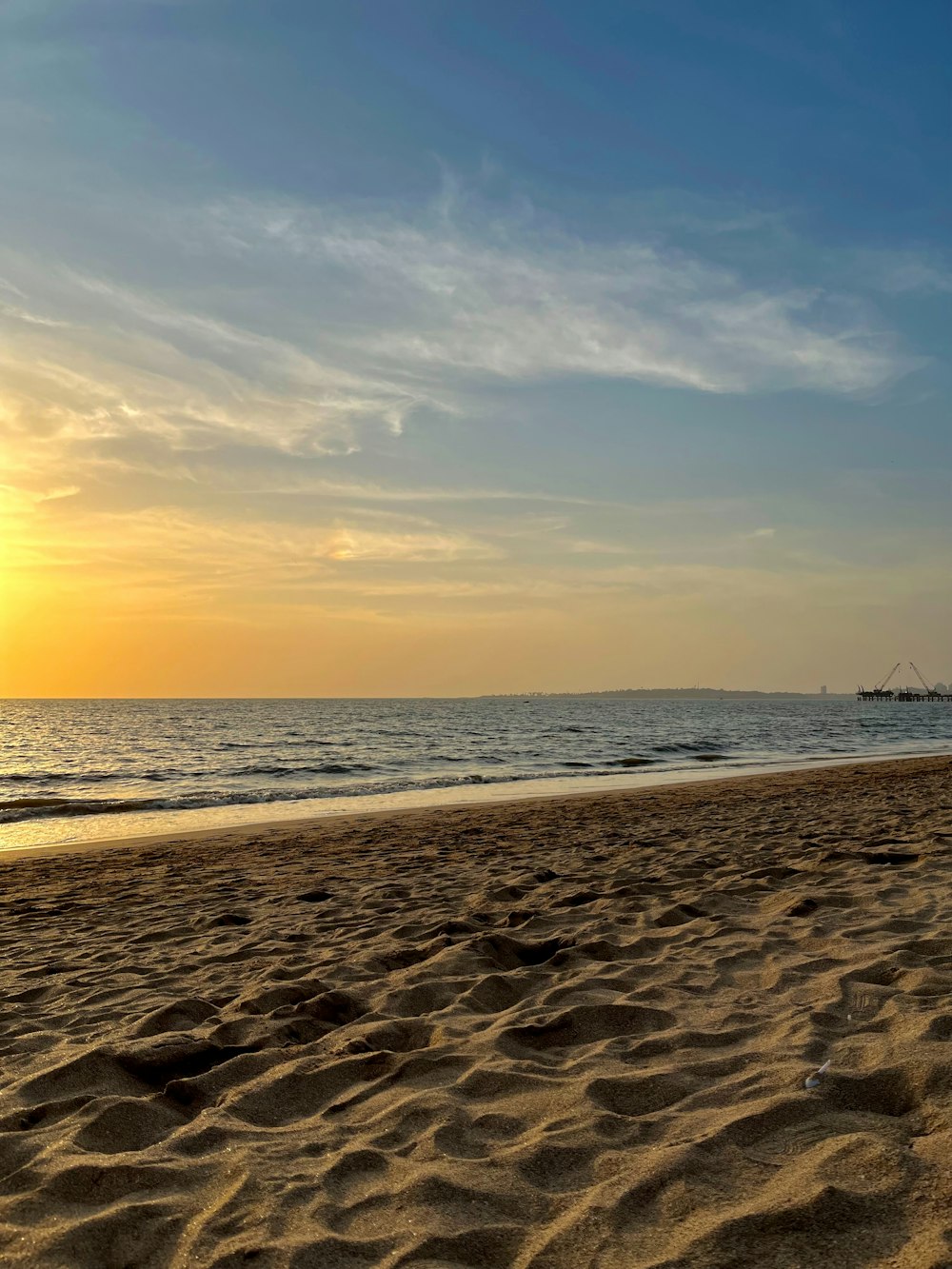 the sun is setting over the ocean on the beach