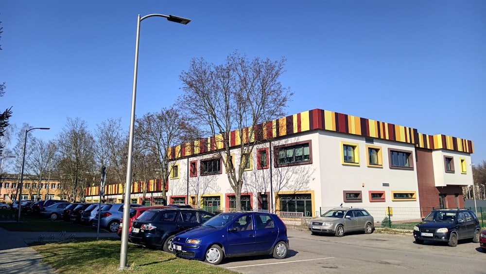 a parking lot with cars parked in front of a multi - colored building