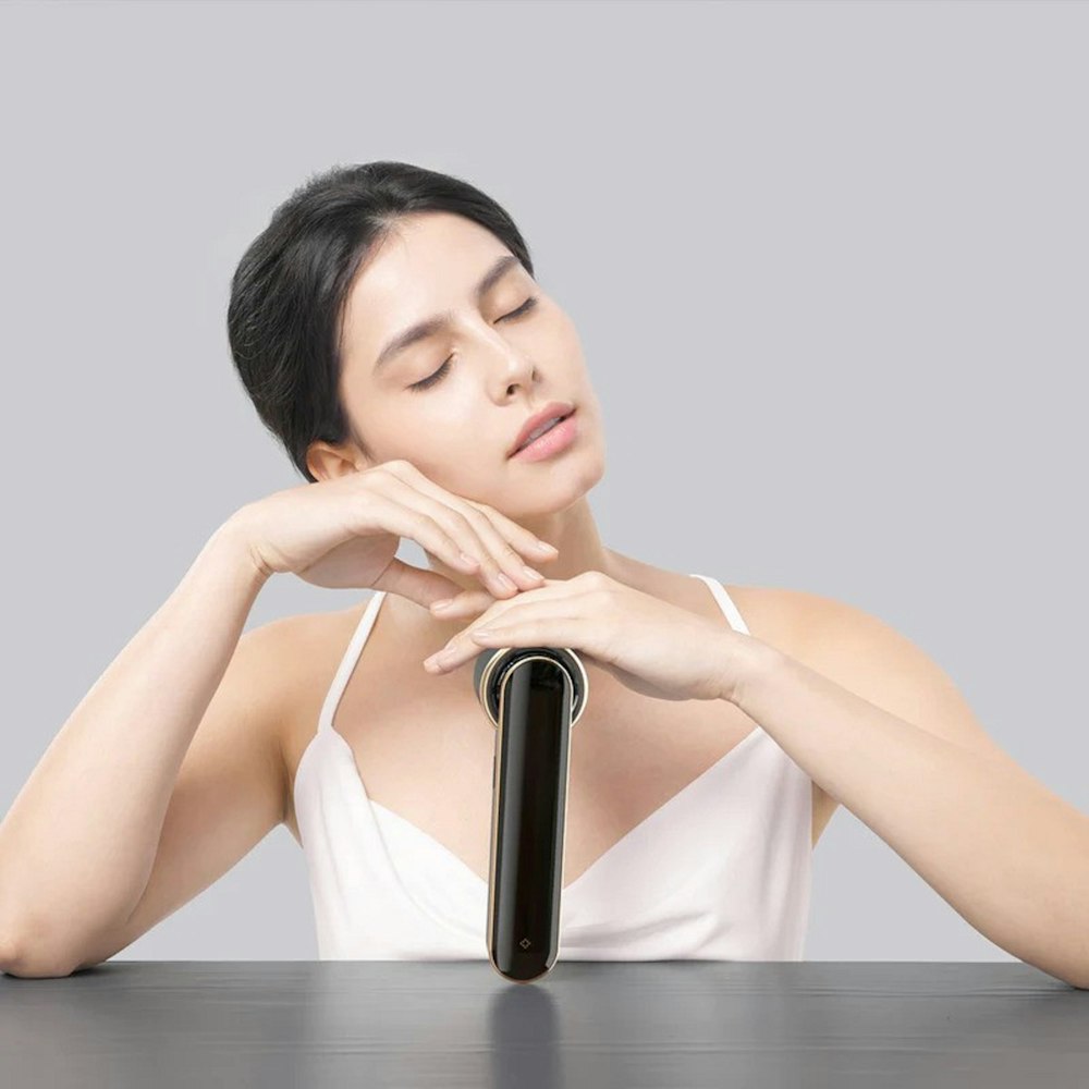 a woman sitting at a table with a hair dryer