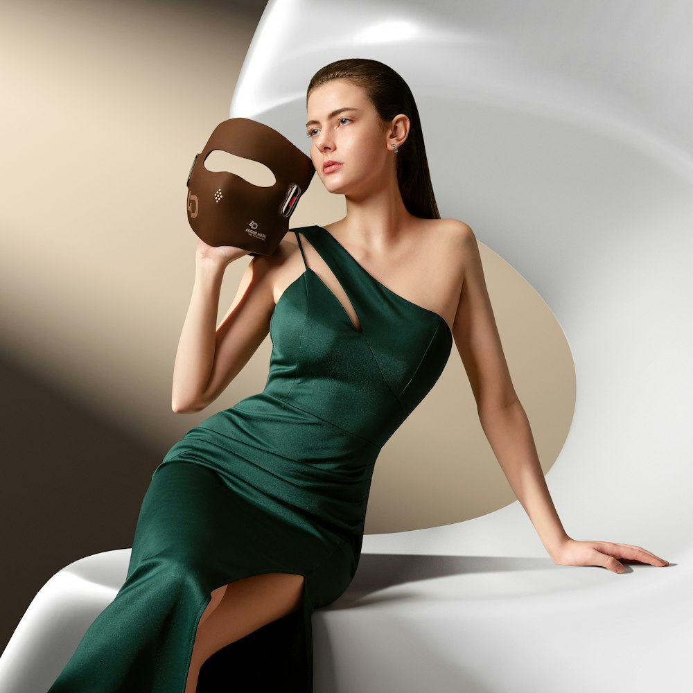a woman in a green dress holding a brown mask