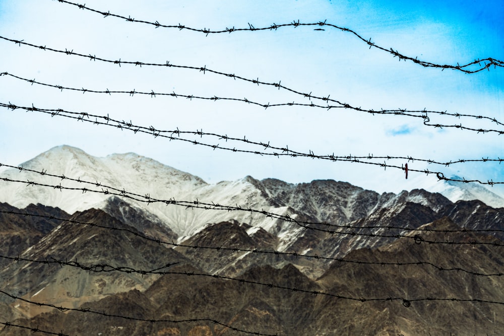 a barbed wire fence with mountains in the background