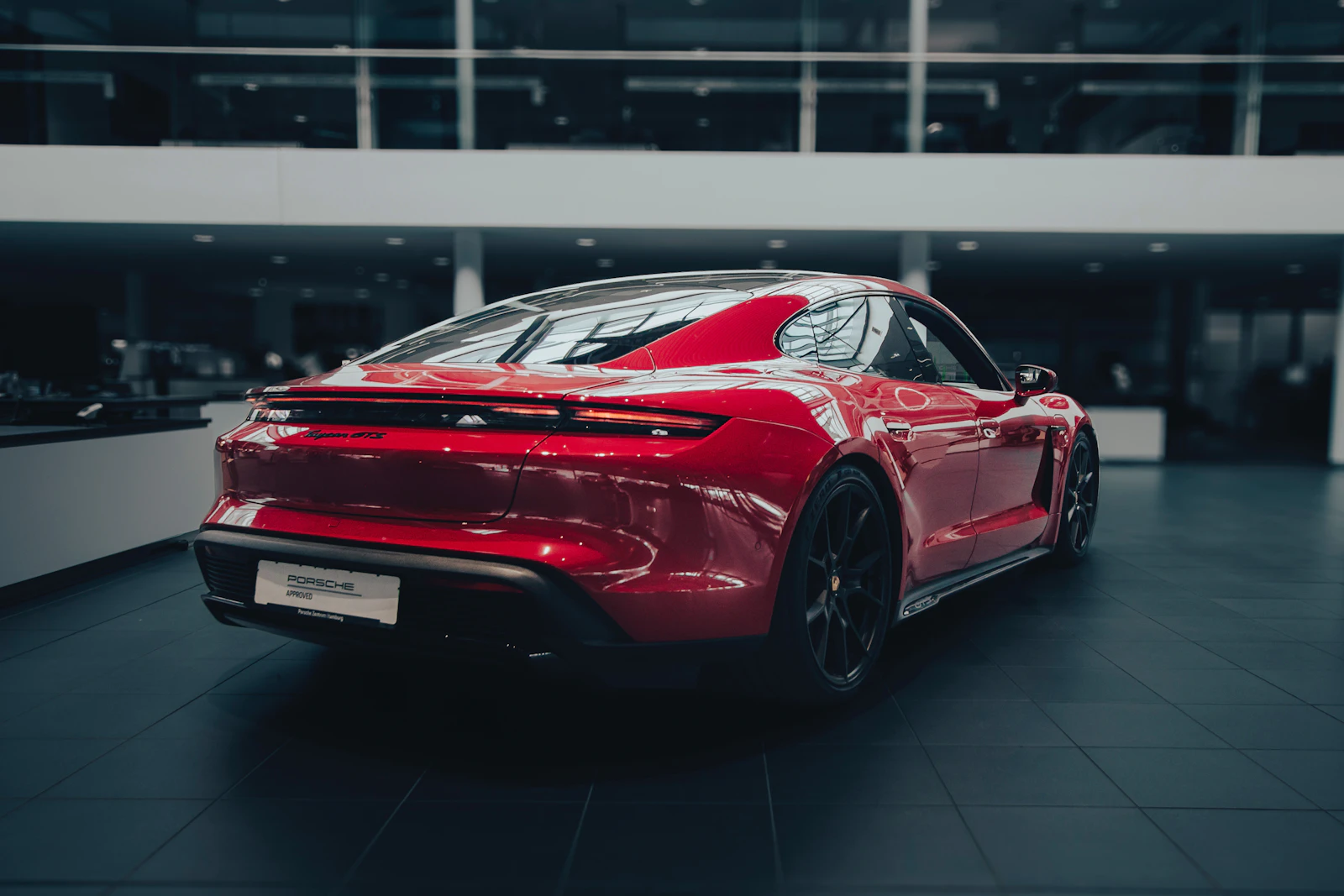 Red Porsche Taycan in a showroom, seen from the rear