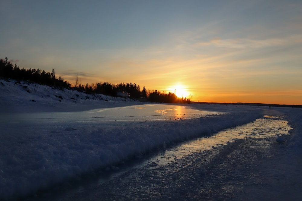 the sun is setting over a frozen river
