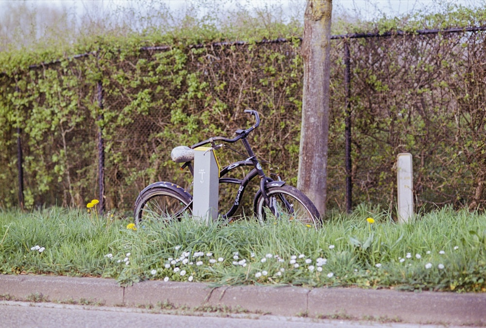 a bicycle is parked in the grass near a fence