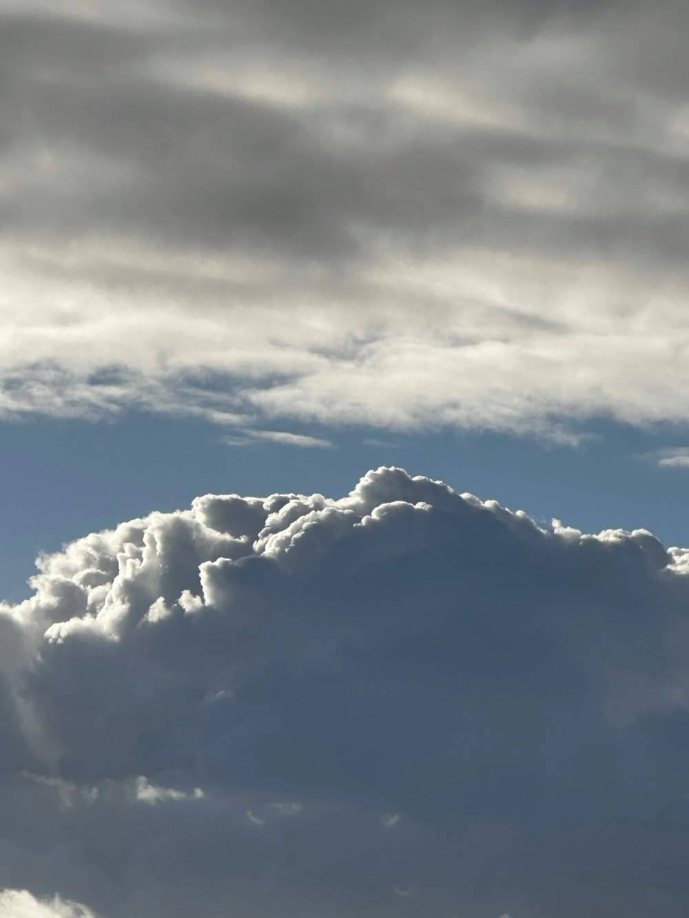 a plane flying through a cloudy blue sky