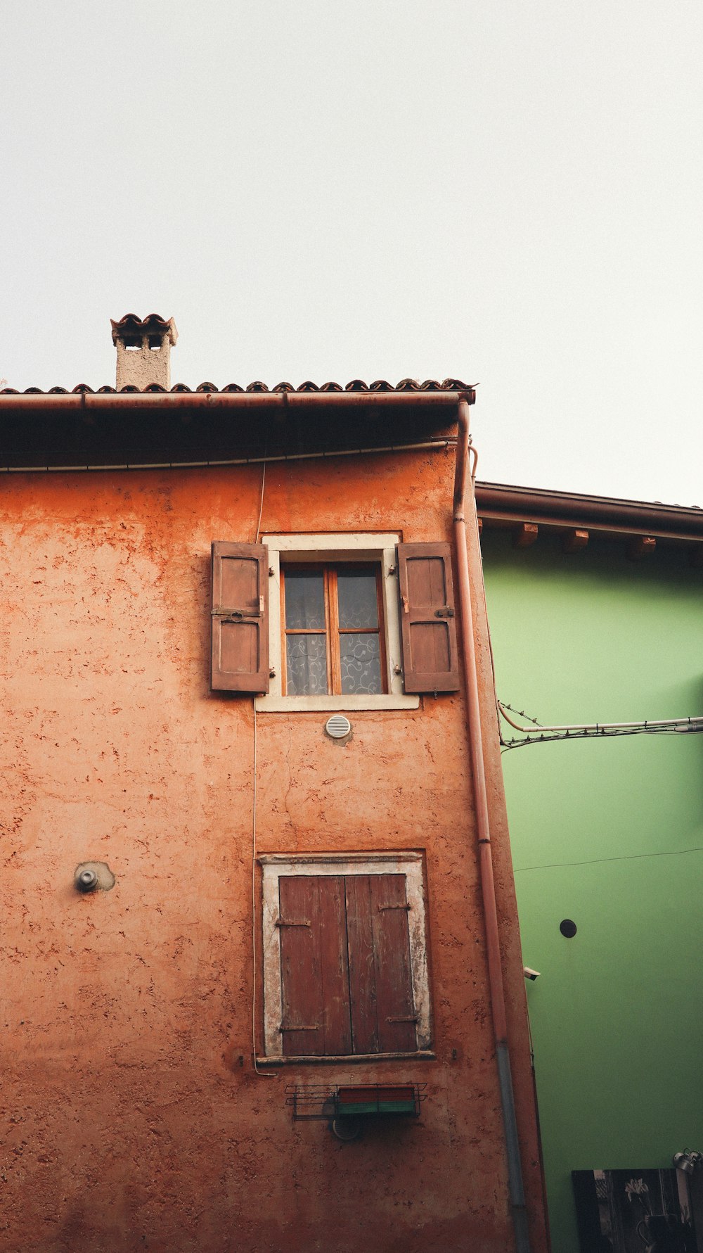 a red building with two windows and a green building