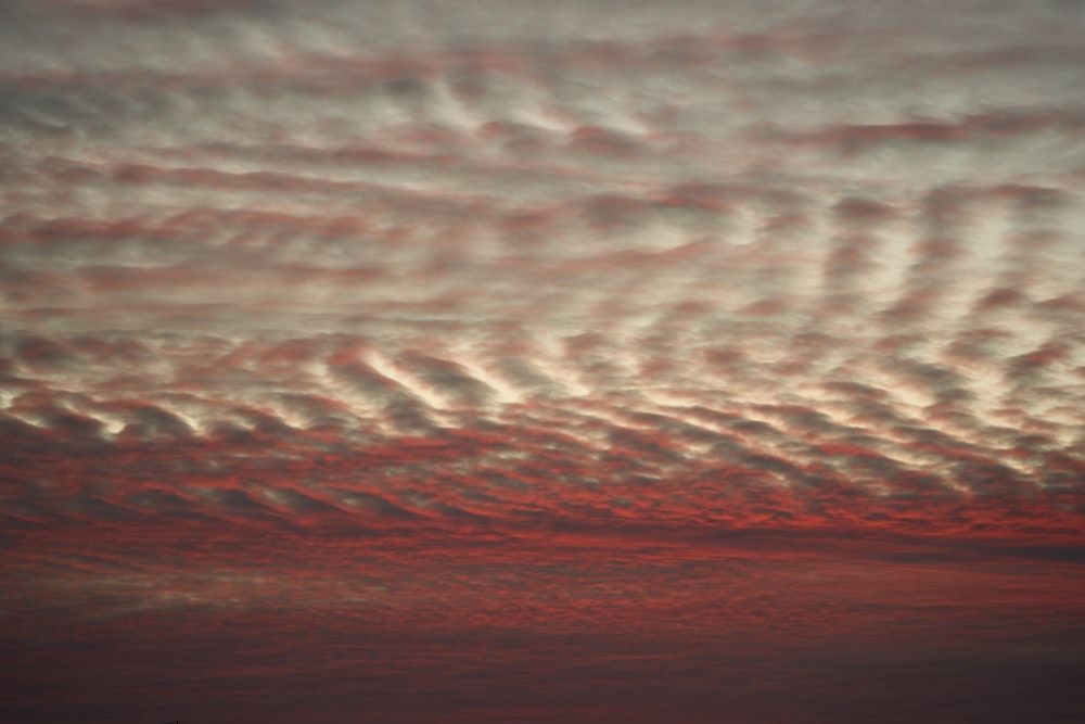 a red sky with clouds and a plane in the distance