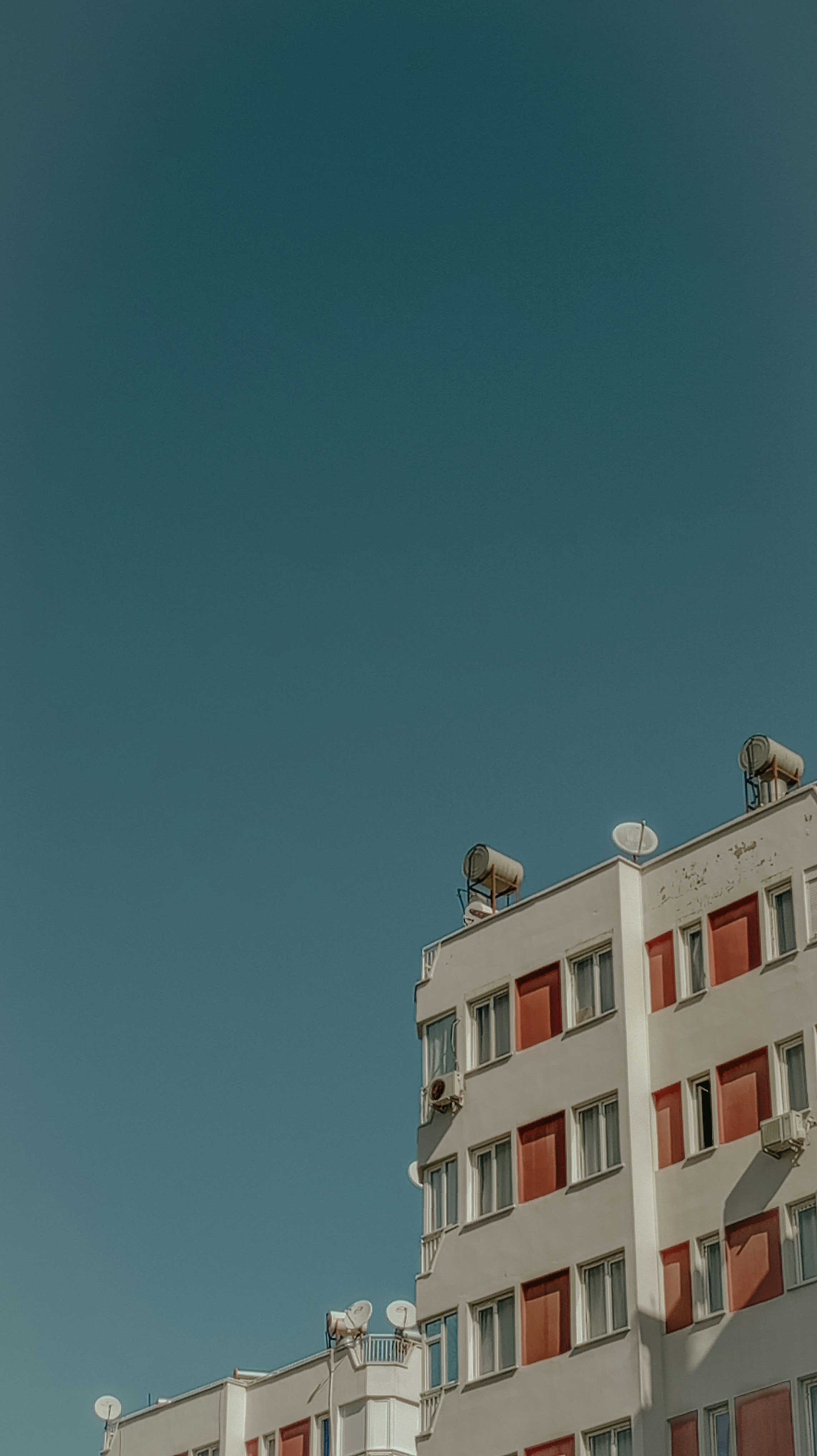 a tall white building with red shutters and windows
