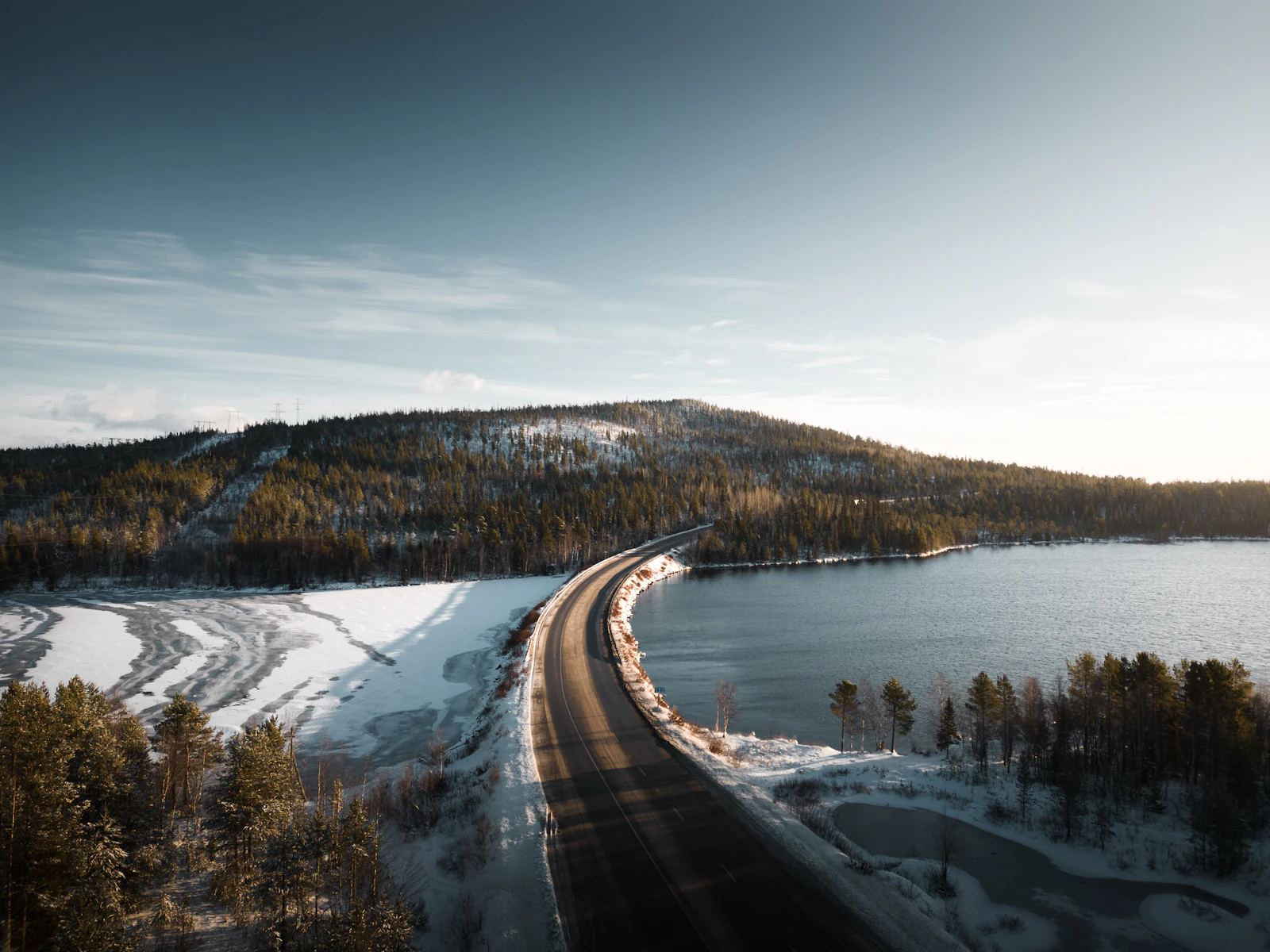 A road across a lake through the snowy hills from the air — Murmansk, Russia