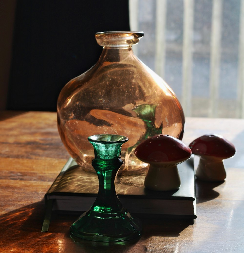 a green glass vase sitting on top of a wooden table