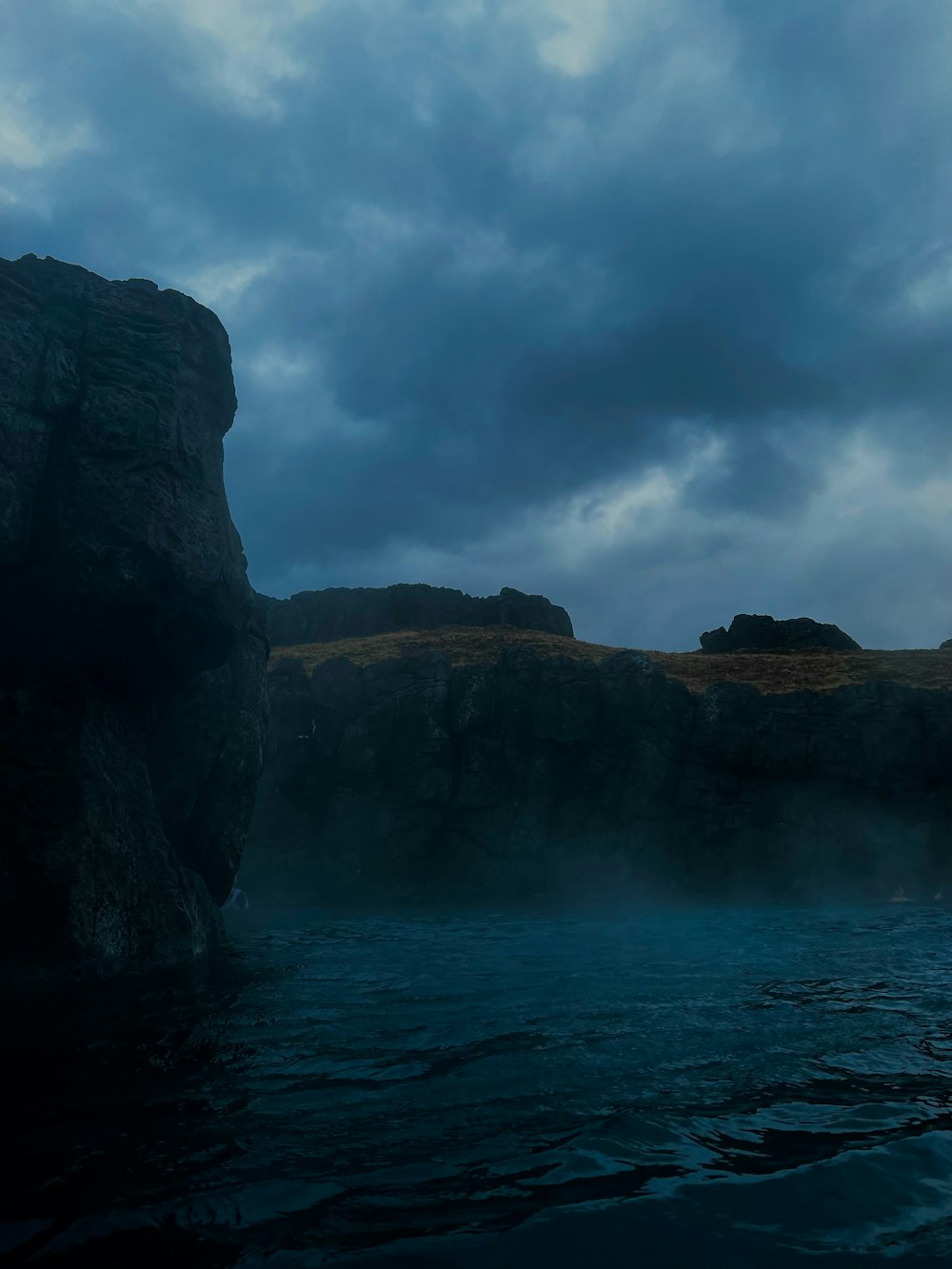 a body of water with a large rock in the middle of it