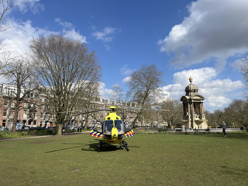 a yellow and black helicopter sitting in the middle of a park