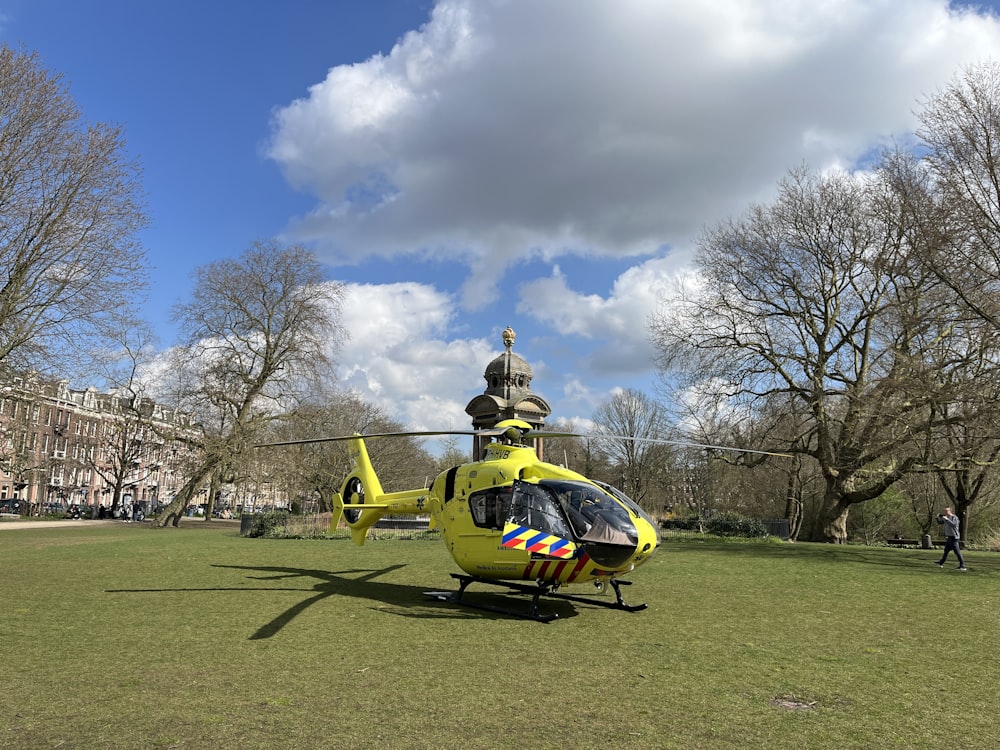 a yellow helicopter sitting on top of a lush green field