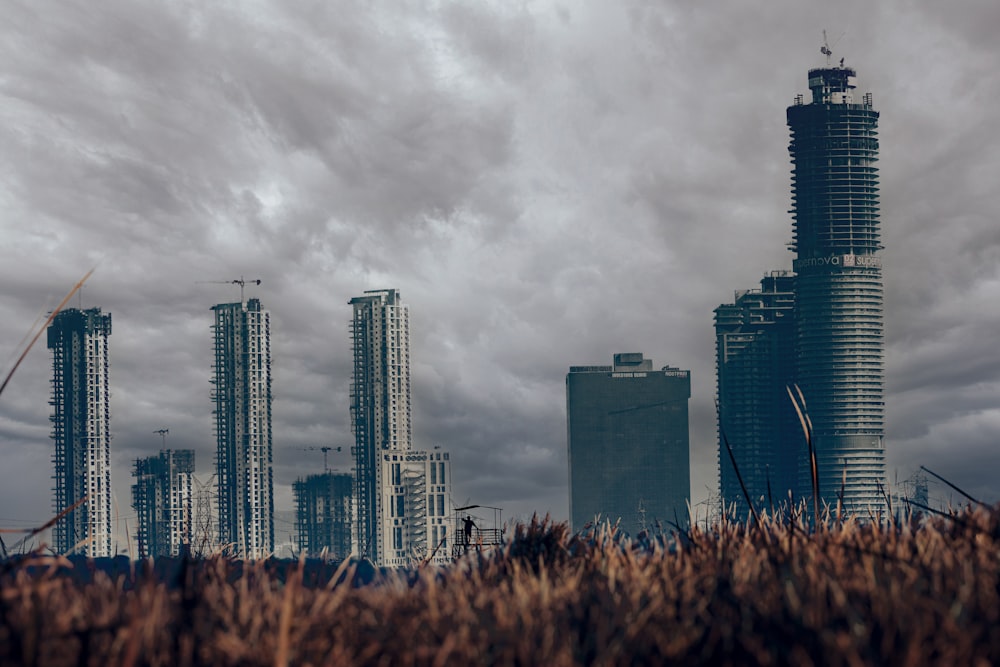 a city skyline with tall buildings under a cloudy sky