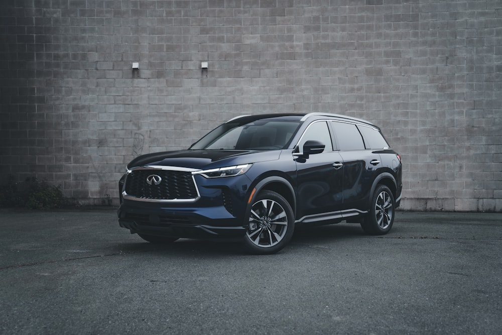 a blue suv parked in front of a brick wall