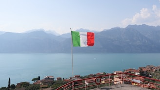 a flag flying on top of a hill next to a body of water