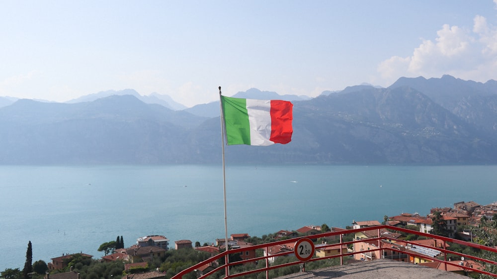 a flag flying on top of a hill next to a body of water