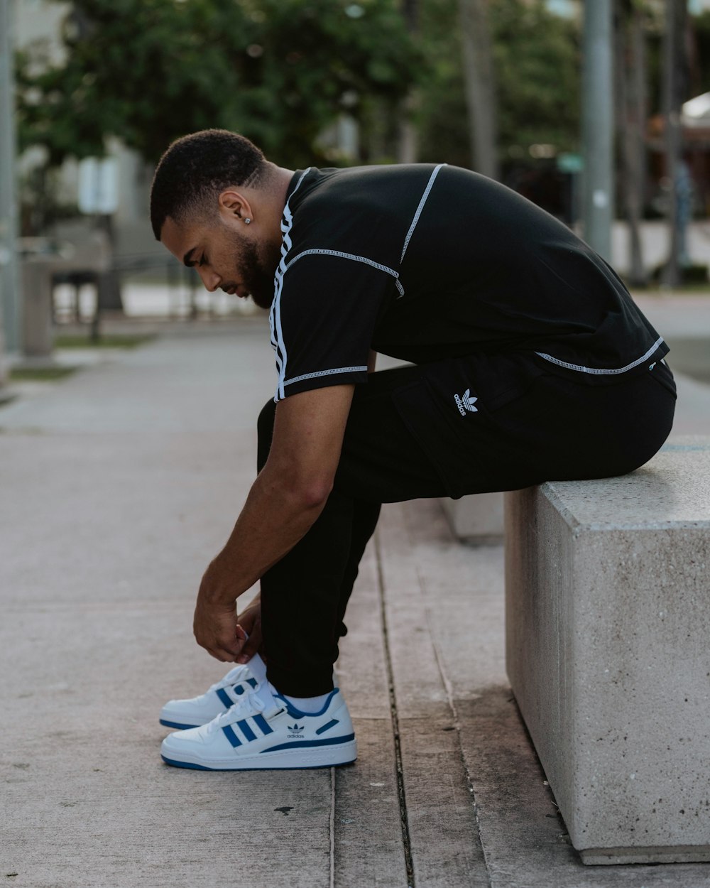 a man sitting on a cement bench tying his shoes