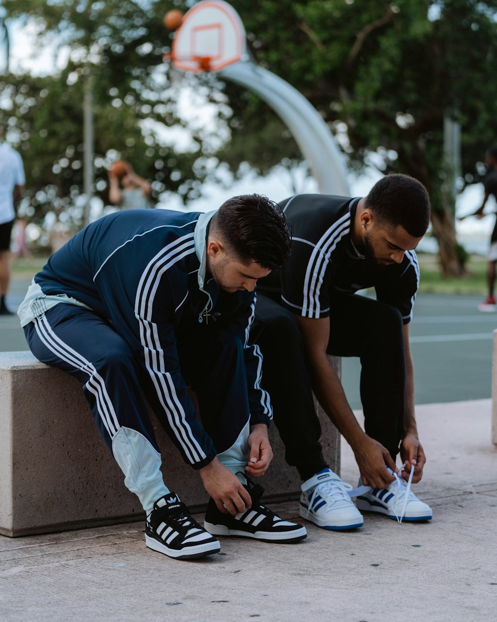 two young men are tying shoes on a bench