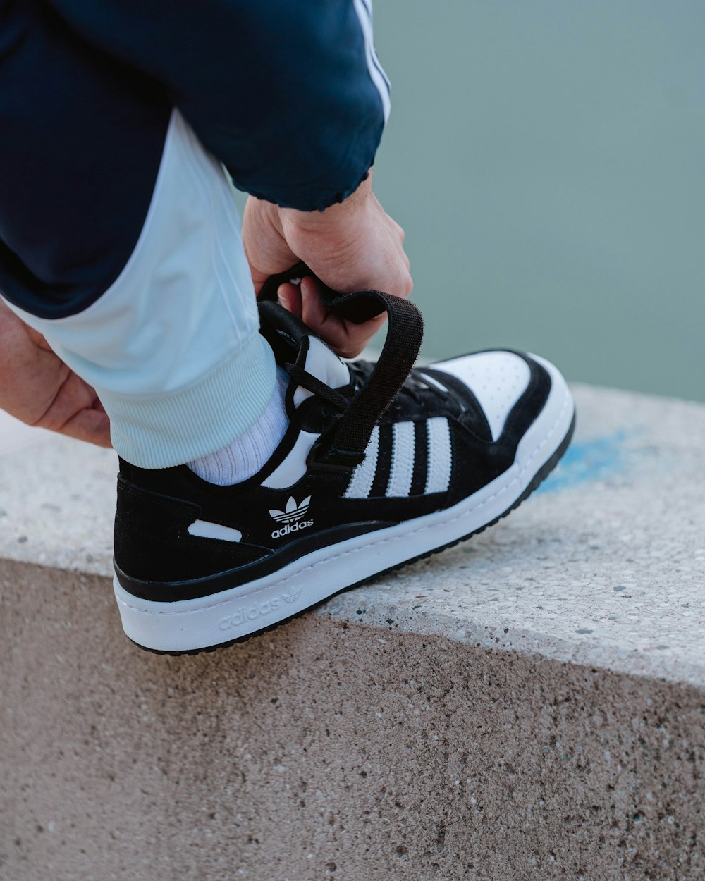 a person tying a shoelace to a black and white sneaker