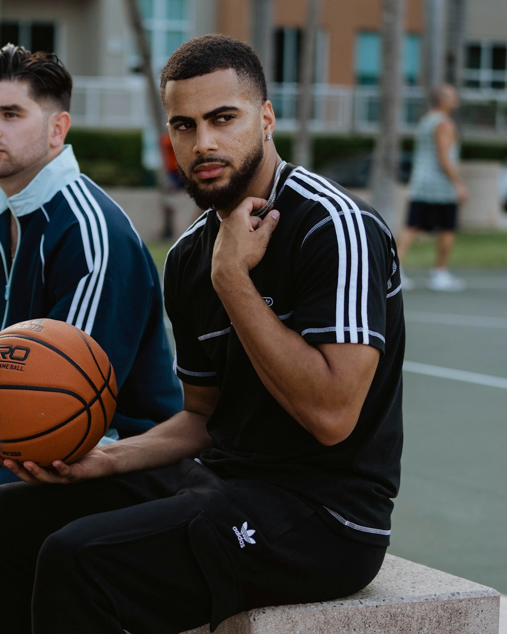 a man holding a basketball sitting next to another man