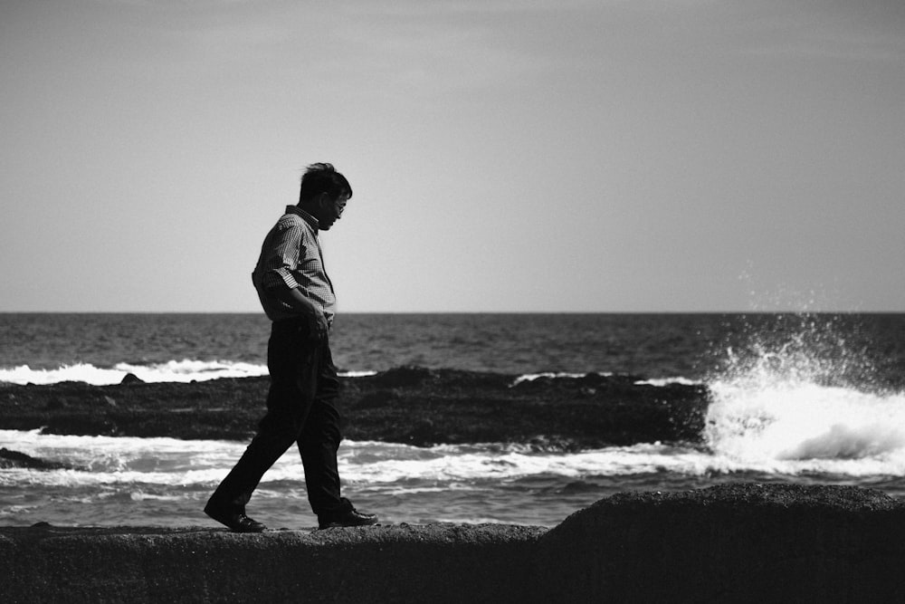 a man walking along a beach next to the ocean