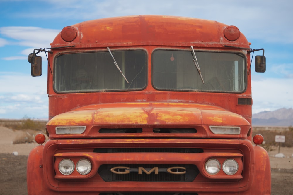 an old orange truck is parked in the desert