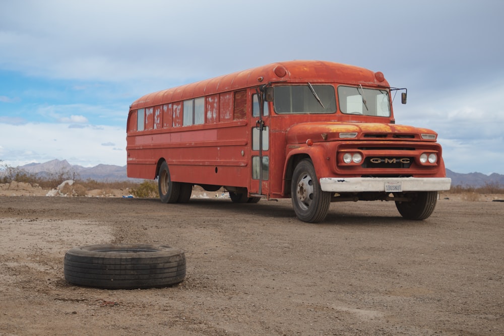 an old red school bus parked in the desert